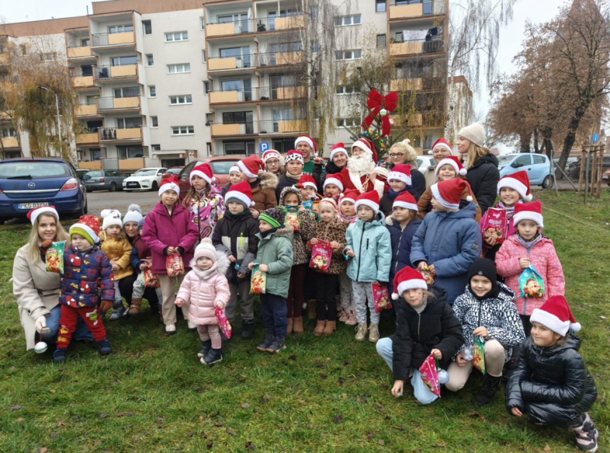 Uśmiechnięte dzieci pozują z Mikołajem podczas osiedlowych Mikołajek w Kościanie.